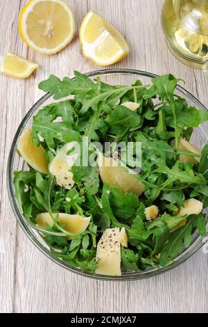 Arugula (razzo) insalata condita scaglie di parmigiano e macinato fresco nero Foto Stock