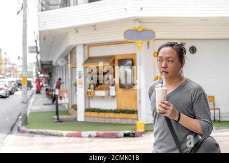 L'uomo asiatico tiene il tè del latte di ghiaccio della palla di bolla davanti al negozio sul sentiero esterno della strada. Foto Stock
