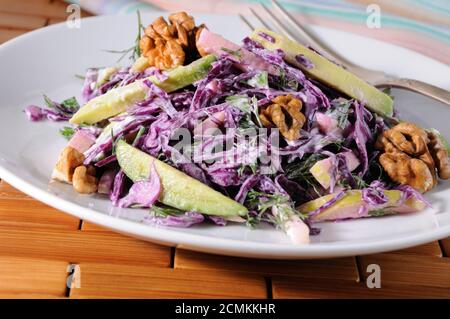 Insalata coleslaw rosso con fette di avocado, Apple, dadi, prezzemolo, aneto condito salsa di yogurt Foto Stock