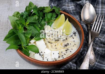 Una zuppa di riso con le tagliatelle e tofu insaporito con limone erba (basilico), il coriandolo, sesamo. Foto Stock