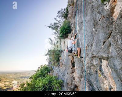 Uomo che arrampica su una roccia ripida e piana in Portogallo Foto Stock