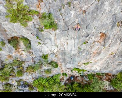 Arrampicarsi in alto sulla roccia mentre un altro lo fissa al piano terra Foto Stock