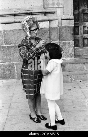 Mazatlan Messico anni '70. Madre e figlia al di fuori della chiesa cattolica romana si stanno preparando. Madre sta fissando la sua testa delle figlie che copre le mantiglie prima che entrino nella chiesa. 1973 HOMER SYKES Foto Stock