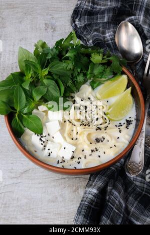 Una zuppa di riso con le tagliatelle e tofu insaporito con limone erba (basilico), il coriandolo, sesamo. Foto Stock