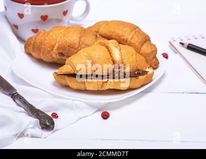 Cornetti al forno con cioccolato su una piastra bianca Foto Stock
