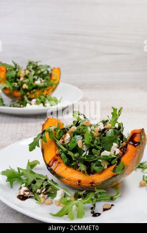 rucola che serve su spicchi di zucca al forno condita con capra formaggio con pinoli e condito con Foto Stock