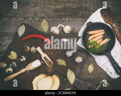 Salsicce in un tondo nero ghisa padella e materie uova di quaglia Foto Stock