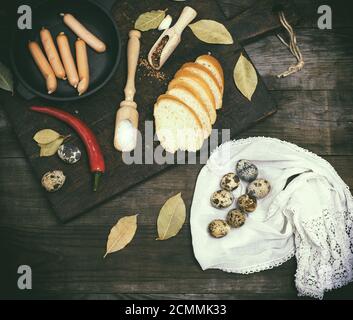 Salsicce in un tondo nero ghisa padella e materie uova di quaglia Foto Stock