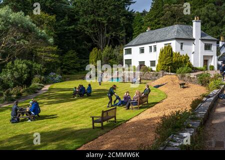 I visitatori si rilassano sul prato di fronte alla Inverewe House a Inverewe Garden, Poolewe, Wester Ross, Scozia, Regno Unito Foto Stock