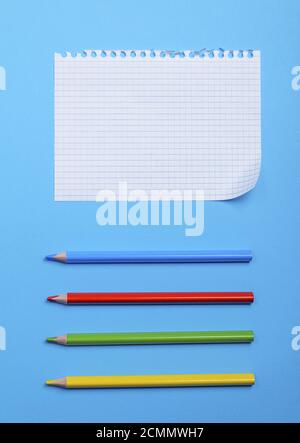 White foglio sbozzato in una scatola da un notebook con fori e multi-colore matite in legno Foto Stock