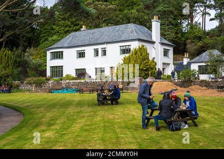 I visitatori si rilassano sul prato di fronte alla Inverewe House a Inverewe Garden, Poolewe, Wester Ross, Scozia, Regno Unito Foto Stock