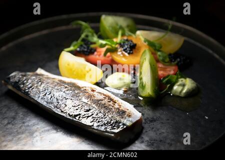 Sgombro con caviale servito con insalata di pomodoro e basilico. Lo sgombro è stato indurito e serrato. Foto Stock