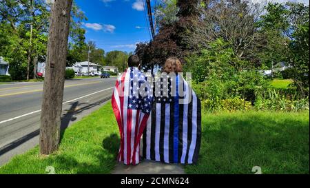 Due persone in piedi, con bandiere sulle spalle, una bandiera americana e l'altra una bandiera sottile linea blu, durante una Blue Lives Matter Parade. Foto di alta qualità Foto Stock