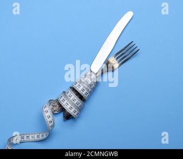 Ferro da stiro forchetta e coltello avvolto in un nastro di misurazione Foto Stock