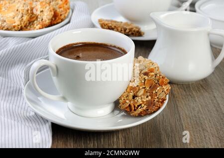 Una tazza di caffè con senza glutine cookies da cereali sul tavolo da caffè. Si tratta di tempo hanno un morso Foto Stock