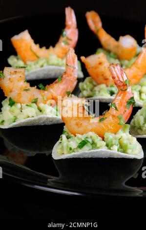 Uno snack leggero di patatine con riempimento di avocado e gamberi fritti aromatizzati con erbe aromatiche. Foto Stock