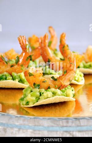 Uno snack leggero di patatine con riempimento di avocado e gamberi fritti aromatizzati con erbe aromatiche. Foto Stock