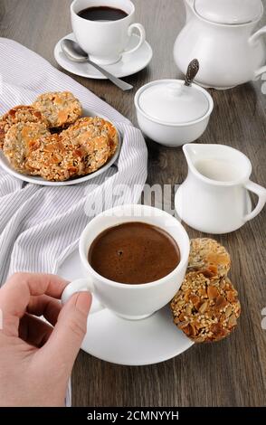 Una tazza di caffè con senza glutine cookies da cereali sul tavolo da caffè. Si tratta di tempo hanno un morso Foto Stock