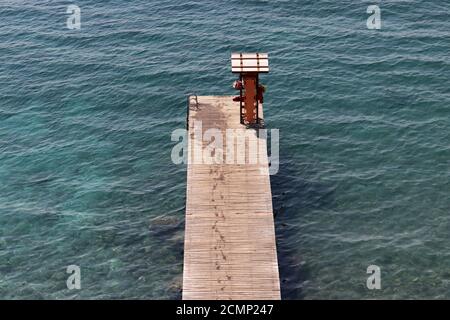 Molo vuoto in legno con impronte bagnate in mare azzurro, vista aerea. Vacanza in spiaggia, concetto di nuoto Foto Stock