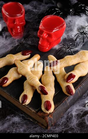 Immergere i biscotti croccanti con shortbread sotto forma di dita di strega In velluto rosso di cioccolato caldo. Questo è jus Foto Stock