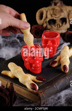 Immergere i biscotti croccanti con shortbread sotto forma di dita di strega In velluto rosso di cioccolato caldo. Questo è jus Foto Stock