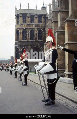 Anni '60, storico, Castello di Windsor, una serie di Queens Guards in servizio cerimoniale. Dal 1660, il privilegio di sorvegliare il Sovrano appartiene alle truppe della famiglia o 'le guardie', che consiste di cinque reggimenti di fanteria - le guardie di Grenadier, Coldsteam, scozzesi, irlandesi e gallesi - e di due reggimenti della Cavalleria domestica - i Giardi di vita e i Blues e Royals. Foto Stock