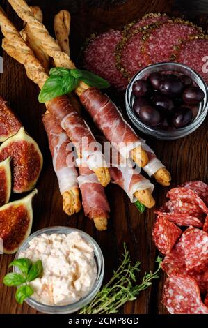 Bastoncini di pane italiano appena sfornati con parmigiano avvolto con una fetta di prosciutto e olive, fi Foto Stock