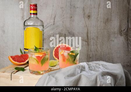 Cocktail di succo di pompelmo rosso spremuto e foglie di limone basilico delicato, fette di lime e peperoncino Foto Stock