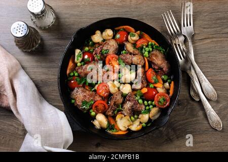 Fritti di fegato di pollo con verdura contorno di pomodori, carote, funghi piselli in padella Foto Stock