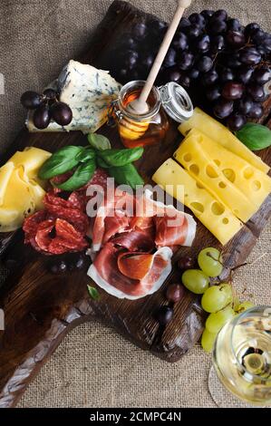 Piatto di catering antipasto con pancetta a strappo, prosciutto, salame, formaggio e uva su una b di legno Foto Stock