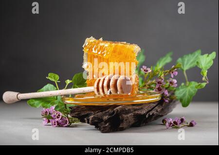 Nidi d'ape, fiori e un cucchiaio di legno su un tavolo di cemento. Foto Stock