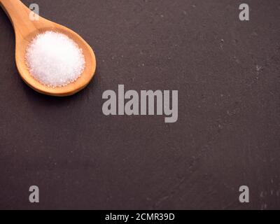 Il cucchiaio di legno con marine sale comune su una piastra di ardesia Foto Stock