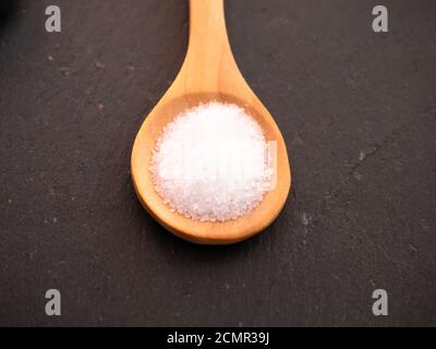 Il cucchiaio di legno con marine sale comune su una piastra di ardesia Foto Stock