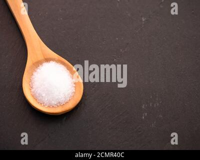 Il cucchiaio di legno con marine sale comune su una piastra di ardesia Foto Stock