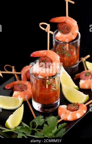 Antipasto di shish kebab con gamberi e chorizo ​​sausages con salsa barbecue in un bicchiere Foto Stock