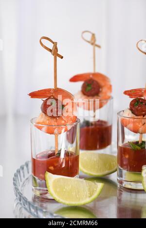 Antipasto di shish kebab con gamberi e chorizo salsicce con salsa barbecue in un bicchiere Foto Stock