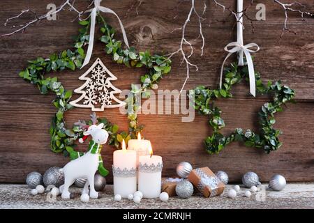 Composizione natalizia con candele, statuine di alce e decorazioni festive su sfondo ligneo. Biglietto d'auguri per Natale o Capodanno. Foto Stock