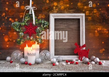 Composizione natalizia con candele, cornice fotografica e decorazioni festive su sfondo ligneo. Biglietto d'auguri per Natale o Capodanno. Foto Stock