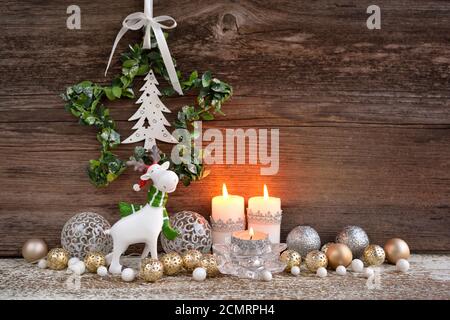 Composizione natalizia con candele, statuine di alce e decorazioni festive su sfondo ligneo. Biglietto d'auguri per Natale o Capodanno. Foto Stock