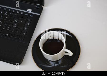 Notebook, dettaglio attrezzatura con tazza da caffè in ceramica bianca con caffè e piattino nero, su sfondo bianco, Brasile, Sud America Foto Stock
