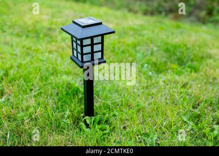 Lampada a celle solari in giardino e risparmiare energia di elettricità E salvare il mio mondo, close up.Charging lampada solare a terra nel giardino durante il giorno di sole Foto Stock