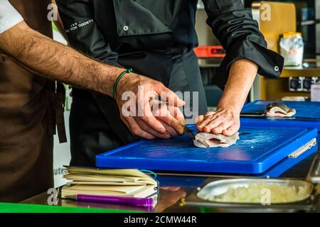 Come si raccorda una trota? Laszlo Papdi spiega la tecnica di taglio in cucina durante un corso presso l'Istituto culinario di Budapest, Ungheria Foto Stock