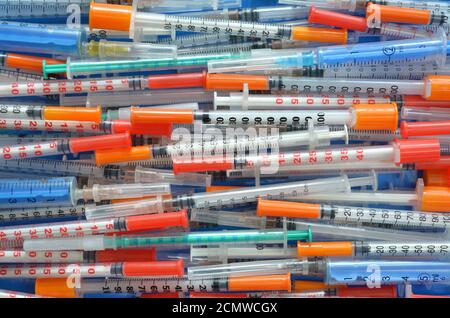 Molte diverse siringhe per insulina da vicino monouso disposte orizzontalmente come sfondo, vista dall'alto. Concetto di assistenza sanitaria. Foto Stock