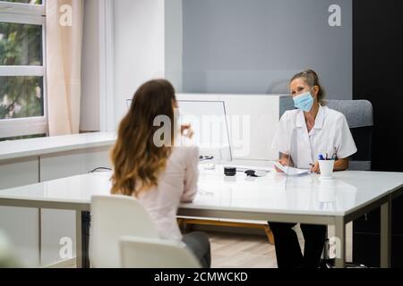 Dottore che parla con il paziente alla riunione di gravidanza con il viso Maschere Foto Stock
