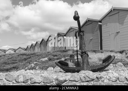 Foto dell'ancora sulla spiaggia di Charmouth con capanne sulla spiaggia sullo sfondo Foto Stock