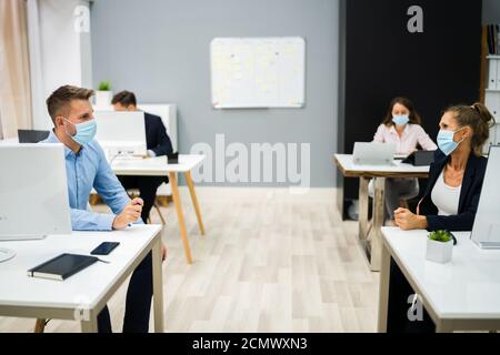 Dipendenti in Business persone che parlano con Social Distancing e faccia Maschere Foto Stock