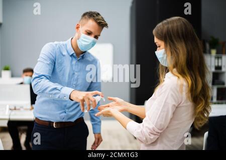 Pulizia delle mani all'ingresso dell'ufficio con igienizzatore antisettico Foto Stock