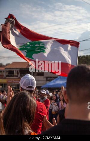 Manifestanti libanesi che innalzano la Bandiera del Libano nel cielo al Rivoluzione contro il governo Foto Stock