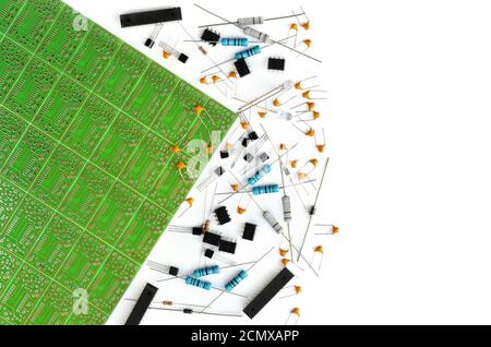 Vari componenti elettronici disposti vicino alla scheda elettronica verde su sfondo bianco con spazio di copia. Primo piano, vista dall'alto Foto Stock