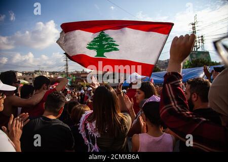 Manifestanti libanesi che innalzano la Bandiera del Libano nel cielo al Rivoluzione contro il governo Foto Stock